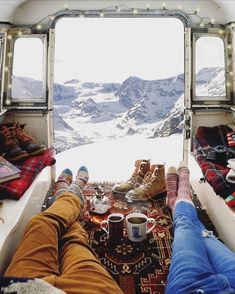 two people sitting in the back of an airplane with their feet up and coffee cups on the ground