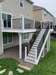 a house with stairs leading up to the second floor and another building in the background