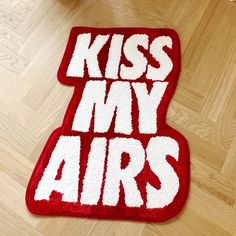 a red and white rug that says kiss my airs on the floor next to a teddy bear