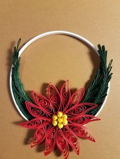 a paper poinsettia on a white hoop with green and red yarn around it