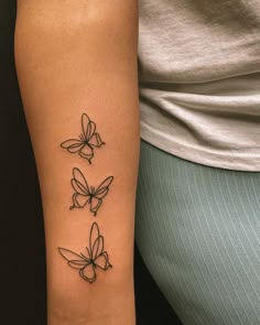 a woman's arm with three butterflies tattoo on the left side of her arm