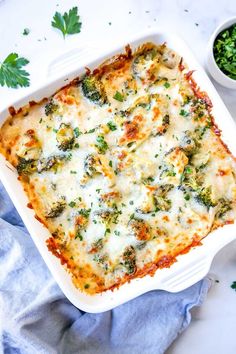 a casserole dish with broccoli and cheese in it on a blue towel