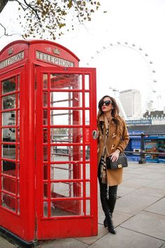 a woman standing next to a red phone booth