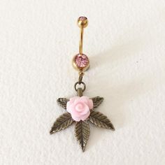 a pink rose and leaf belly ring on a white background