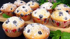 muffins with berries and powdered sugar on a wooden tray next to flowers