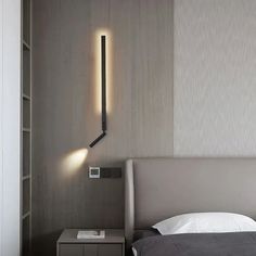 a bed sitting under a wall mounted light next to a book shelf in a bedroom