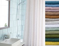 a white sink sitting under a bathroom mirror next to a bathtub filled with towels