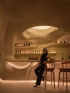 a woman is sitting at a bar with two stools