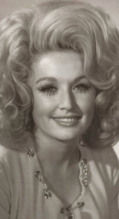 an old black and white photo of a woman with blonde hair wearing a beaded necklace