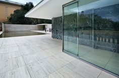 an empty patio with glass walls and trees in the background