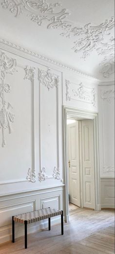 an empty room with a bench in the middle and white wallpaper on the walls