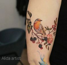 a bird sitting on top of a branch with berries and leaves around its neck tattoo