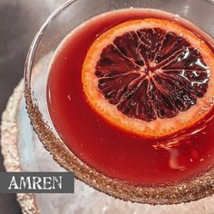 a blood orange drink in a glass with ice and garnish on the rim