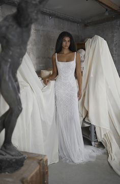 a woman in a white dress standing next to sculptures