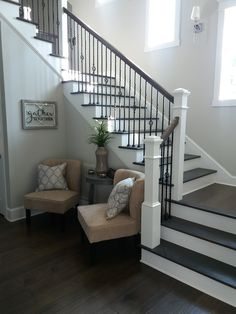 a living room with two chairs and a stair case