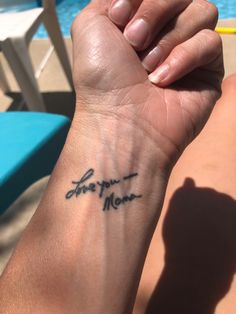 a person with a tattoo on their arm near a swimming pool and chair, holding onto the wrist