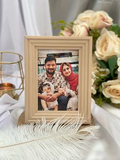 a wooden frame with a photo of two people and a dog on it next to some flowers