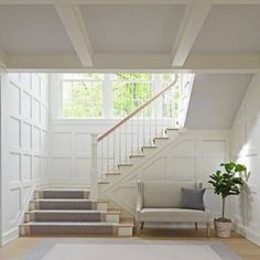 a living room filled with furniture and a stair case next to a white staircase leading up to a second story window