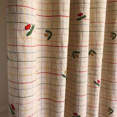 a curtain with red flowers on it in front of a white wall and window sill