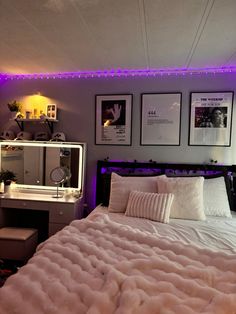 a bedroom with purple lights and pictures on the wall above the bed, along with a vanity