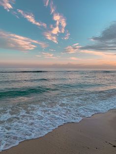 the ocean waves come in to shore as the sun sets over the water and clouds