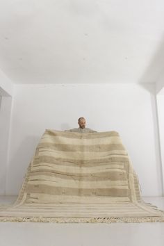 a man sitting on top of a large blanket in a room with white walls and flooring