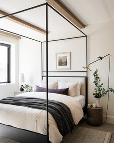 a bedroom with a four poster bed and white walls