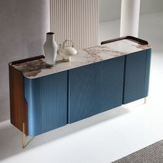 two vases sitting on top of a blue cabinet next to a white and brown wall