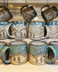 several coffee mugs with designs on them sitting on a table next to each other