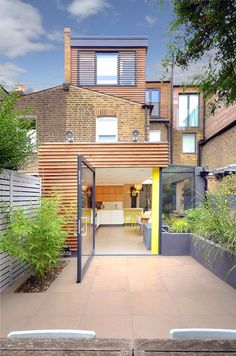 an open patio with benches and plants in front of a brick building on a sunny day