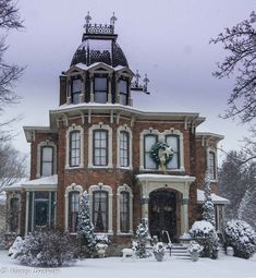 a large brick house covered in snow with a wreath on the front door and windows