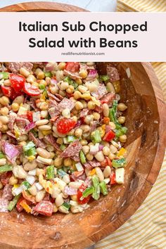 a wooden bowl filled with salad and beans on top of a yellow striped table cloth