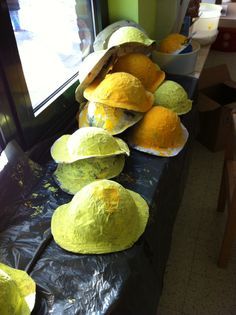 several yellow hats are lined up on a table in front of a window with plastic covering over them