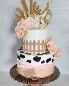 a three tiered cake decorated with pink and white flowers on a table next to a wall