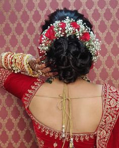 the back of a woman's head with flowers in her hair and bracelets