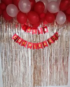 a bunch of balloons and streamers hanging from the ceiling in front of a curtain