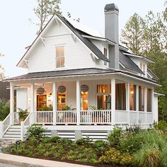 a white house with porches and balconies on the front, surrounded by greenery