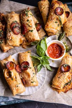 several pastries are on a plate with sauce and herbs next to the plates that have them