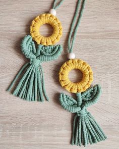 two necklaces with tassels and beads hanging on a wooden surface, one is yellow and the other is green