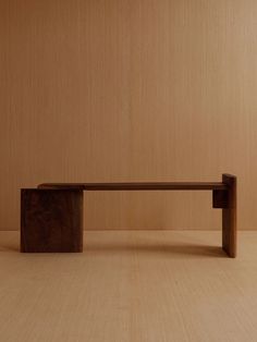 a wooden bench sitting on top of a hard wood floor next to a brown wall