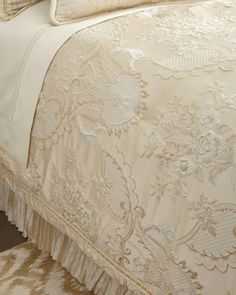 an image of a bed that is made up with white and beige bedspreads