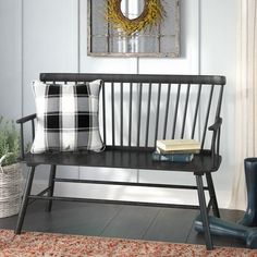 a black bench sitting in front of a painting on the wall next to a window