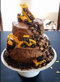 a three tiered chocolate cake with construction vehicles on top