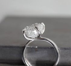 a white diamond ring sitting on top of a metal table next to a black book