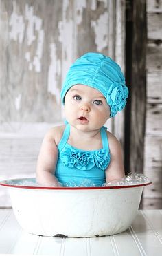 a baby sitting in a bowl with a blue hat on it's head and the words have a wonderful day