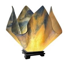 a lamp that is sitting on top of a black stand with an orange and yellow design