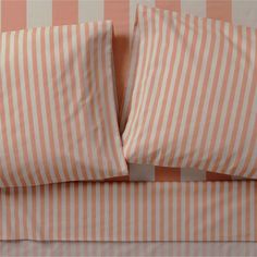 an orange and white striped bed spread with two pillow cases on top of each other