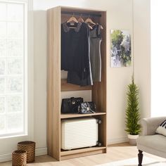 an open wooden closet with clothes and luggage