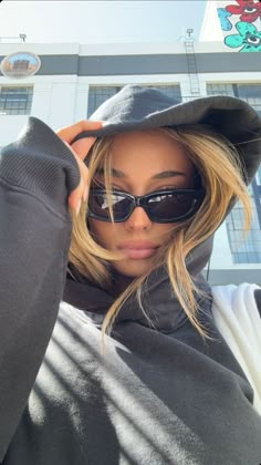 a woman wearing sunglasses and a hoodie