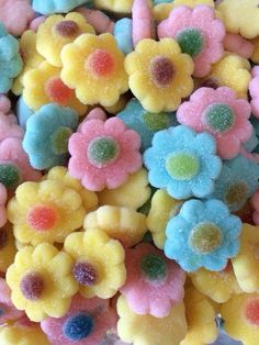 there are many different colored candies in the bowl with flowers on them for decoration